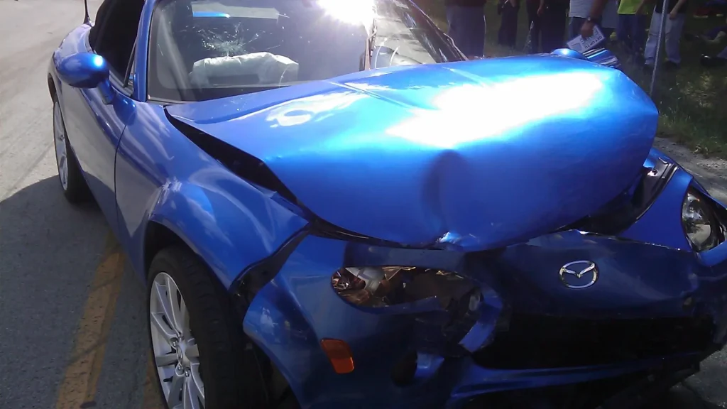 Close-up of a blue car with significant front-end damage from a collision.