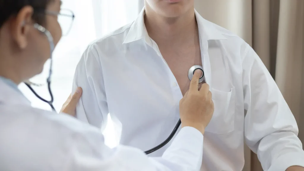 A healthcare professional using a stethoscope to check a patient's chest during a medical examination.